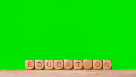 Education-Concept-With-Wooden-Letter-Cubes-Or-Dice-Spelling-Education-Against-Green-Screen-Background